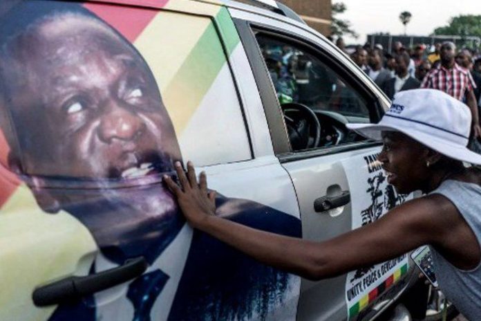 Warga Zimbabwe pendukung pemerintahan baru menyentuh gambar calon presiden baru Emmerson Dambudzo Mnangagwa.(MARCO LONGARI / AFP)