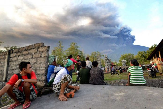 Warga Bali menonton erupsi Gunung Agung terlihat dari Kubu, Karangasem, Bali, 26 November 2017. Gunung Agung terus menyemburkan asap dan abu vulkanik dengan ketinggian yang terus meningkat, mencapai ketinggian 3.000 meter dari puncak. Letusan juga disertai dentuman yang terdengar sampai radius 12 kilometer.(AFP PHOTO / SONNY TUMBELAKA)