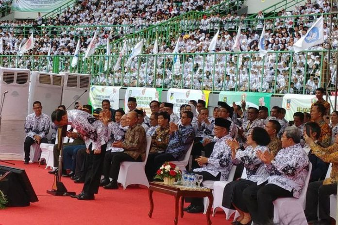 Presiden Joko Widodo menundukkan badan untuk memberi hormat kepada guru yang hadir dalam peringatan hari ulang tahun Persatuan Guru Seluruh Indonesia (PGRI) dan Hari Guru Nasional 2017 di Stadion Patriot Candrabhaga, Bekasi, Sabtu (2/12/2017).(KOMPAS.com/IHSANUDDIN)