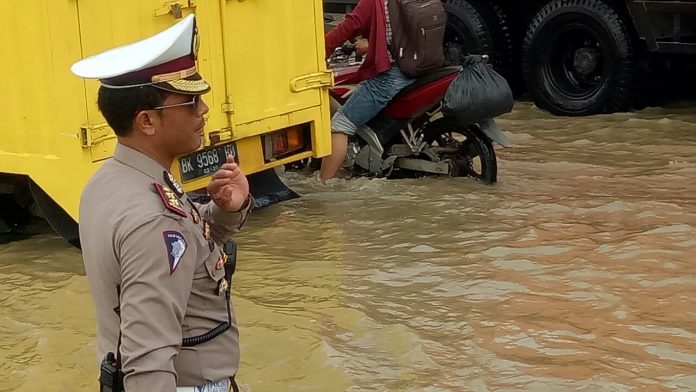 Kasat Lantas Polrestabes Medan AKBP Muhammad Saleh mengatur arus lalu lintas di Jalan Sisingamangaraja persis di dekat perumahan Rivera. Orang nomor satu di Satlantas Polrestabes Medan ini langsung turun mengatur lalin karena terjadi perlambatan arus dikarenakan banjir melanda, Senin (4/12/2017)