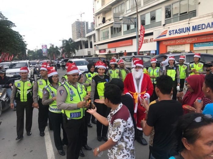 Kasat Lantas Polrestabes Medan, AKBP Muhammad Saleh memberikan hadiah kepada warga yang melintas di seputaran Lapangan Merdeka. Hal ini dilakukan untuk menyambut Natal dan Tahun Baru 2018, Sabtu (23/12/2017)