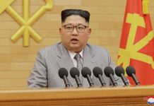 Pencitraan Kim Jong-un dengan Jas Warna Terang Kim Jong-un mengenakan jas abu-abu saat menyampaikan pidatonya. Analis menyebut pilihan itu untuk menunjukkan citra lebih santai. (KCNA/via REUTERS)